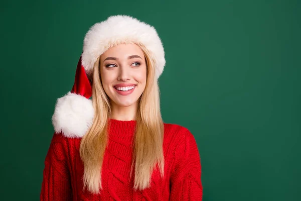 Foto di bella donna positiva guardare spazio vuoto indossare cappello di Babbo Natale sorriso isolato su sfondo di colore verde — Foto Stock