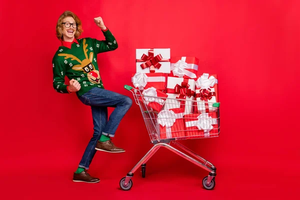 Foto von aufgeregten Glückspilz gekleidet Print-Pullover kaufen viele Geschenk-Boxen steigen Fäuste lächelnd isoliert rote Farbe Hintergrund — Stockfoto