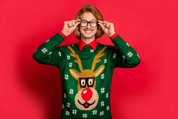 Porträtt av attraktiv glad kille bär festlig pullover vidröra specifikationer isolerade över ljus röd färg bakgrund — Stockfoto