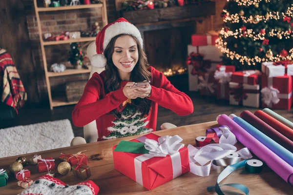 Foto van glimmende schattige jonge dame dragen gebreide trui hoed spijkeren foto van cadeautjes binnen huis kamer — Stockfoto