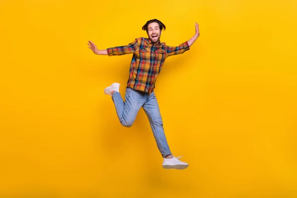 Pleine longueur photo de joyeux brunet millénial gars courir porter chemise jeans baskets isolé sur fond jaune — Photo