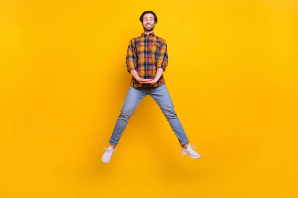 Helkroppsfoto av cool brunett ung kille hoppa bära skjorta jeans sneakers isolerad på gul bakgrund — Stockfoto