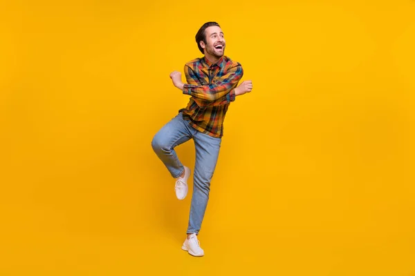 Full body photo of cute brunet young guy dance wear shirt jeans sneakers isolated on yellow background — Stock Photo, Image