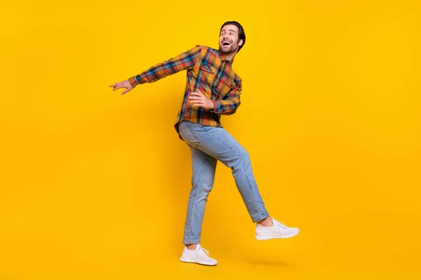 Foto in voller Größe von fröhlichen brünetten Millennial Kerl Tanz tragen Hemd Jeans Turnschuhe isoliert auf gelbem Hintergrund — Stockfoto