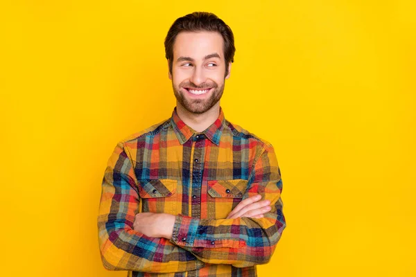 Zdjęcie pewny siebie młody facet ubrany w kratkę ramiona koszuli skrzyżowane patrząc puste miejsce uśmiechając się odizolowany żółty kolor tła — Zdjęcie stockowe