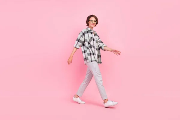 Full storlek profil foto av trevlig ung brunett dam gå bära glasögon skjorta byxor sneakers isolerad på rosa bakgrund — Stockfoto
