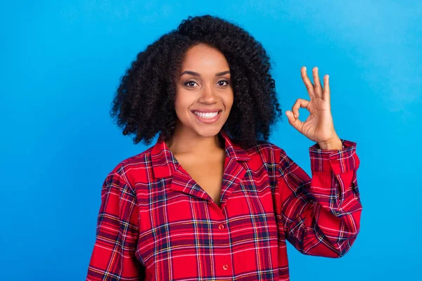 Foto de doce milenar senhora morena mostrar okey desgaste vermelho xadrez pijama isolado no fundo de cor azul — Fotografia de Stock