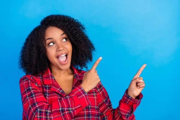 Foto de mujer morena joven asombrada indican mirada espacio vacío desgaste rojo a cuadros pijama aislado sobre fondo de color azul —  Fotos de Stock