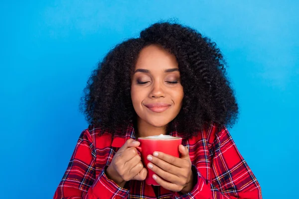 甘い残りの千年の女性の飲み物のコーヒーの写真は、青の色の背景に隔離された赤いチェッカーのパジャマを身に着けています — ストック写真