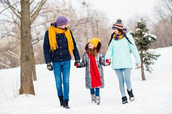 Pleine longueur photo de famille maman papa fille marcher parc hiver journée enneigée tenir la main heureux sourire positif — Photo