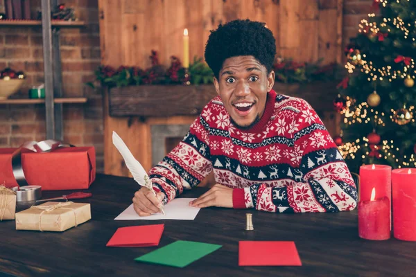 Фотопортрет молодой человек вне себя от радости пишет письмо Санта-Клаусу на Рождество зимние каникулы в украшенной квартире — стоковое фото
