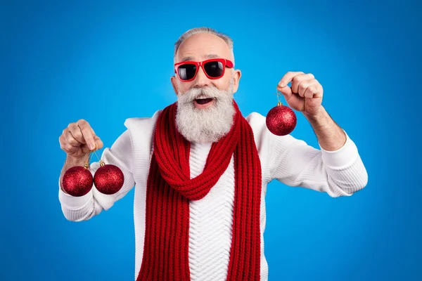 Photo d'âge assez excité gentleman porter pull lunettes rouges souriant tenant décorations de Noël isolé fond de couleur bleue — Photo