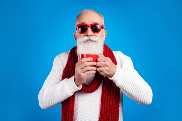 Фото сладкий смешной возраст джентльмен носить белый свитер красные очки улыбаясь наслаждаясь кофе изолированный синий цвет фона — стоковое фото