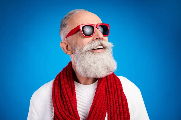 Foto de encantador caballero de edad dulce usar suéter blanco gafas rojas sonriendo buscando espacio vacío aislado color azul fondo —  Fotos de Stock