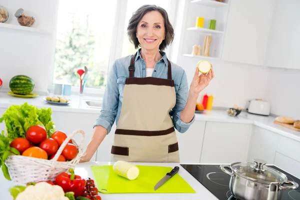 Foto des Alters gute Dame geschnitten Zucchini tragen Schürze Jeans Hemd in der Küche allein — Stockfoto