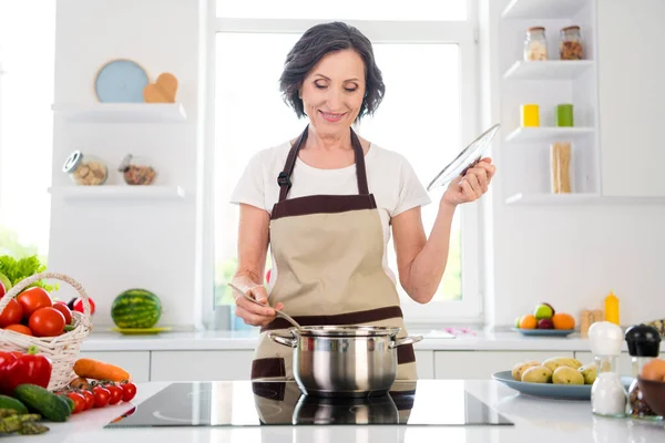 Фото веселого позитивного гарного настрою жінка посміхається, щоб зробити суп насолоджуватися в приміщенні всередині домашньої кухні — стокове фото