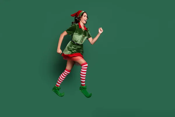Lunghezza completa dimensione del corpo vista di attraente allegra ragazza motivata elfo salto in esecuzione isolato su sfondo di colore verde — Foto Stock