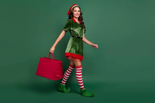 Full kropp profil sida foto av ung flicka glad positiv leende gå promenad butik säsong försäljning butik isolerad över grön färg bakgrund — Stockfoto