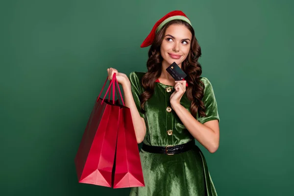 Photo de jeune fille heureux sourire positif rêve penser tenir sacs à provisions carte bancaire noel isolé sur fond de couleur verte — Photo