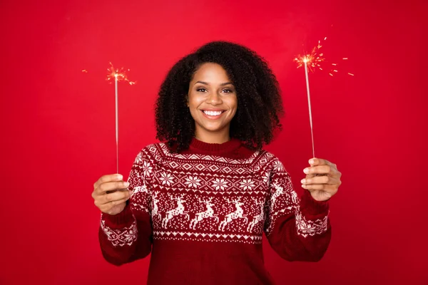 Foto retrato sorridente menina feliz em vermelho jumper sorrindo mantendo luzes bengala isolado vívida cor vermelha fundo — Fotografia de Stock