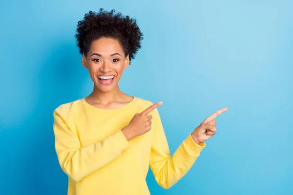 Foto de emocionada mujer afro americana dedo dedo mirada espacio vacío noticias venta aislado sobre fondo de color azul — Foto de Stock