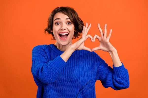 Фотопортрет женщина улыбается показывая сердце с пальцами сверх радостный изолированный ярко-оранжевый цвет фона копипространство — стоковое фото