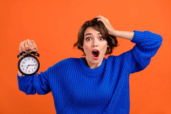 Photo of impressed brunette millennial lady hold clock wear blue pullover isolated on orange color background — Stock Photo, Image