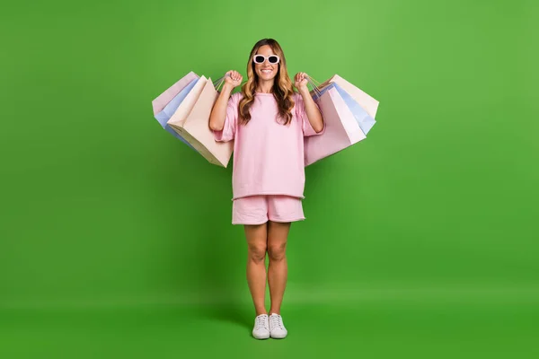 Foto de impressionado muito jovem senhora desgaste rosa camisa óculos escuros crescente pechinchas sorrindo isolado cor verde fundo — Fotografia de Stock