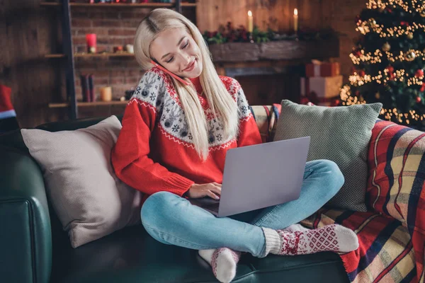 Porträt eines attraktiven, fröhlichen Mädchens, das auf einem Sofa sitzt und mit einem Laptop telefoniert — Stockfoto