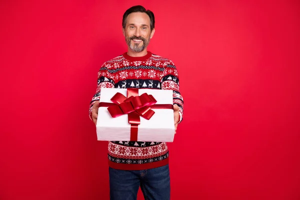Foto retrato homem em suéter maravilhado dando caixa de presente festivo em férias de inverno isolado cor vermelha vívida fundo — Fotografia de Stock
