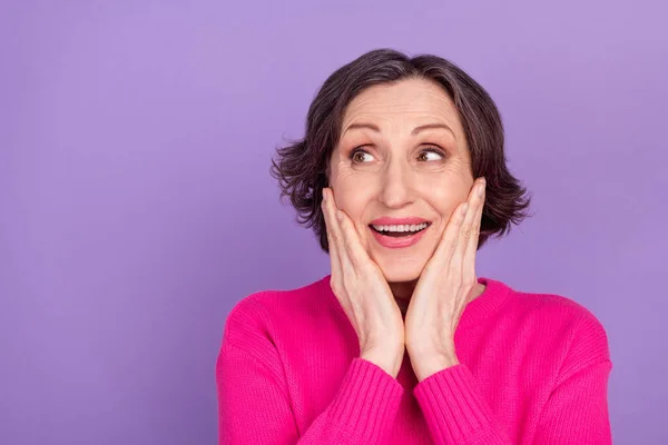 Foto de mulher idosa feliz sorriso positivo mãos toque bochechas espantado olhar vazio espaço isolado sobre cor violeta fundo — Fotografia de Stock