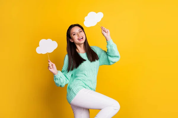 Foto de mujer joven alegre positiva usar gafas sostienen las nubes en palos aislados en el fondo de color amarillo —  Fotos de Stock