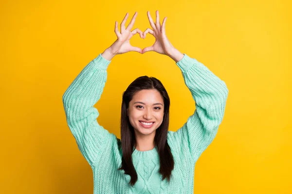 Foto de encantador feliz jovem bonito segurar dedos forma do coração acima da cabeça isolada no fundo de cor amarela — Fotografia de Stock