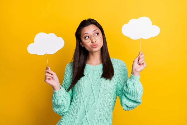 Photo of minded young dreamy woman look empty space hold hands clouds isolated on yellow color background — Stock Photo, Image