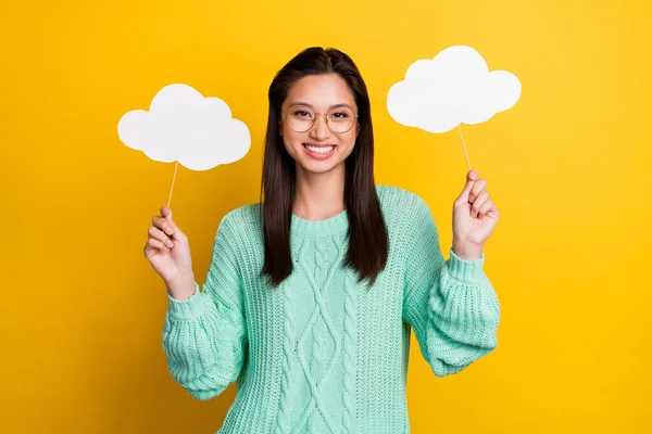 Foto de encantadora jovem feliz usar óculos segurar as mãos nuvens tempo isolado no fundo de cor amarela — Fotografia de Stock