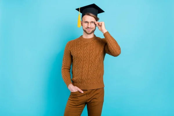 Foto av attraktiv ung positiv man bära glasögon examen hatt leende isolerad på blå färg bakgrund — Stockfoto