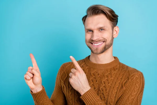Фото привлекательного счастливого молодого человека указывать пальцами пустое пространство продажи новости изолированы на синем фоне цвета — стоковое фото