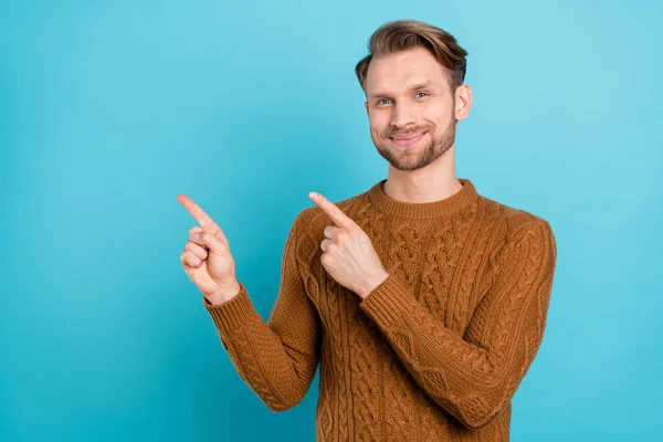 Foto de atraente jovem feliz encantador homem apontar dedos vazio espaço notícias isoladas no fundo de cor azul — Fotografia de Stock