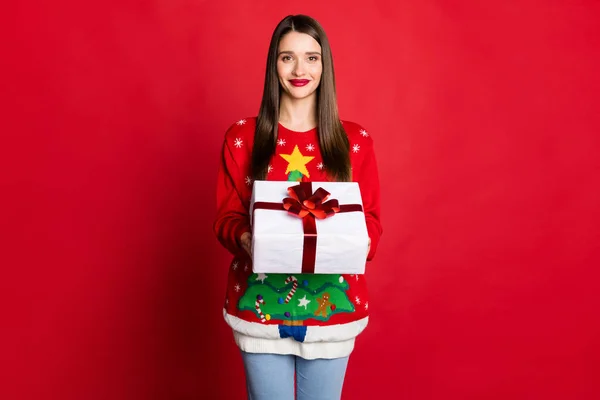 Foto di adorabile dolce giovane signora indossare maglione ornamento in possesso di braccia scatola presente sorridente isolato colore rosso sfondo — Foto Stock