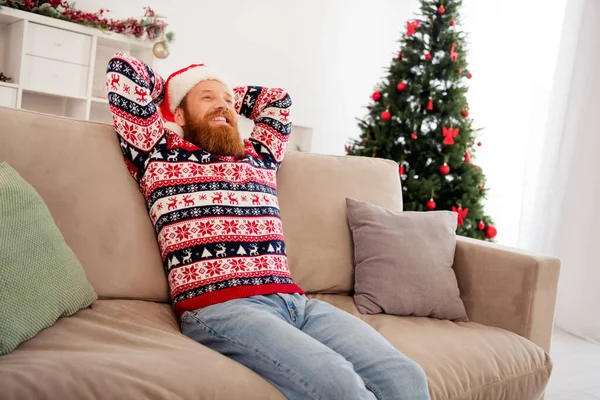 Foto av gott humör avkopplande leende manliga slitage ful röd tröja sitta soffa njuter fritid fira nyår God jul hemma — Stockfoto