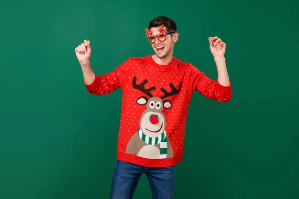 Foto retrato homem em vermelho pulôver de malha óculos engraçados rindo dançando isolado cor verde fundo — Fotografia de Stock