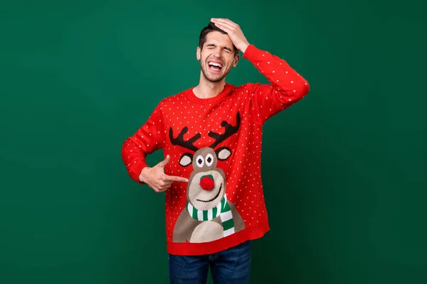 Foto retrato sorrindo homem apontando para camisola de malha engraçada com renas rindo isolado fundo cor verde — Fotografia de Stock