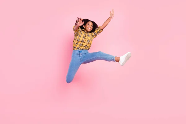 Foto de impressionado funky escuro pele senhora desgaste xadrez camisa saltando alto olhando vazio espaço sorrindo isolado cor-de-rosa fundo — Fotografia de Stock