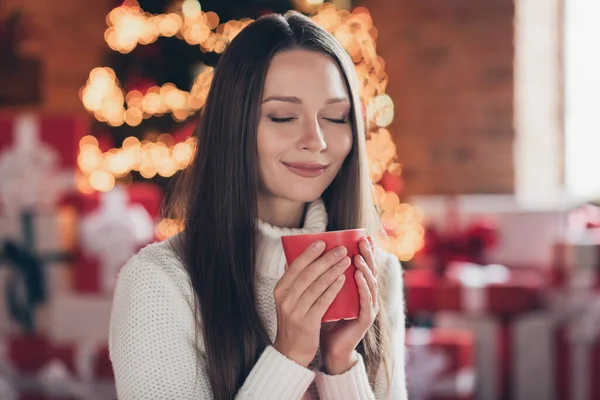 Photo de rêveuse douce jeune femme habillée pull blanc jouissant de boissons chaudes les yeux fermés souriant intérieur chambre maison maison — Photo