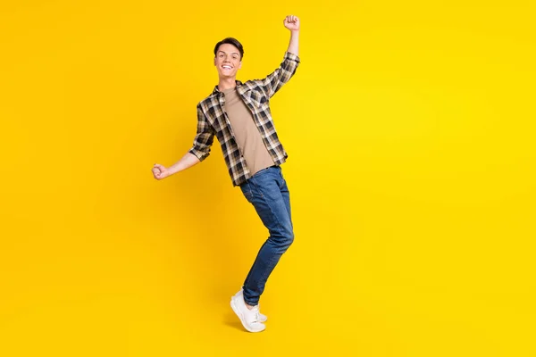 Foto de cara positivo surpreso comemorar vitória desgaste xadrez camisa jeans sapatos isolado cor amarela fundo — Fotografia de Stock