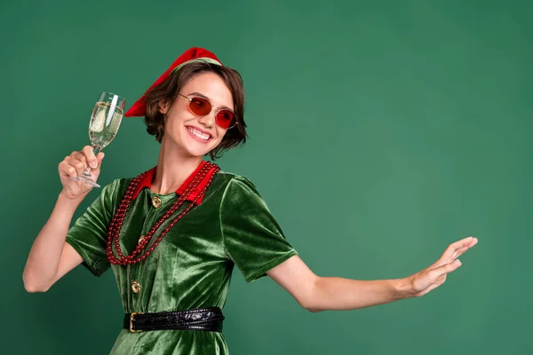 Foto di divertente bella giovane donna vestita elfo occhiali costume sorridente bere champagne ballare isolato colore verde sfondo — Foto Stock