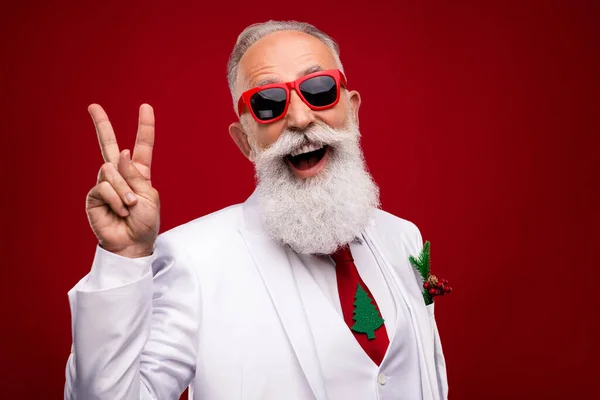 Photo de gai vieil homme cool faire signe v bonne humeur porter cravate arbre Noël isolé sur fond de couleur rouge — Photo