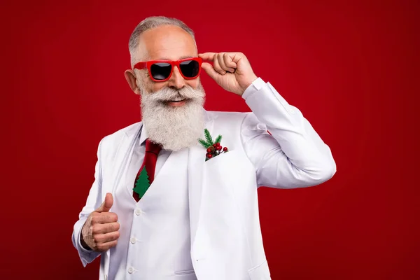 Photo positive heureux charmant vieil homme regarder vide espace porter lunettes de soleil Noël isolé sur fond de couleur rouge — Photo