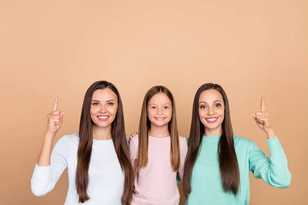 Retrato de três lindas meninas alegres da moda abraçando mostrando anúncio espaço cópia isolado sobre fundo cor pastel bege — Fotografia de Stock