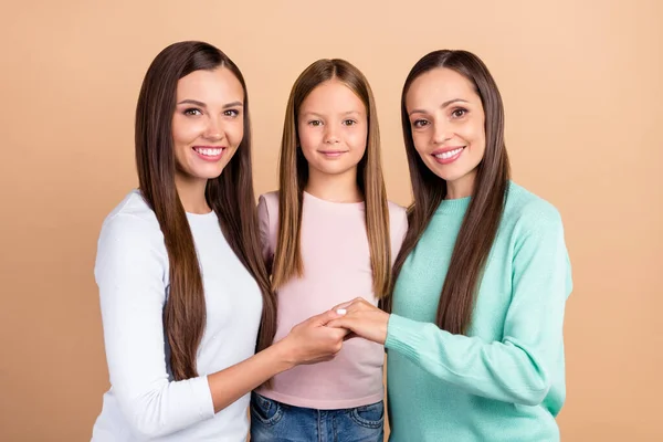 Fotografie veselé pozitivní rodina žena držet ruce péče harmonie izolované na pastelové béžové barvy pozadí — Stock fotografie
